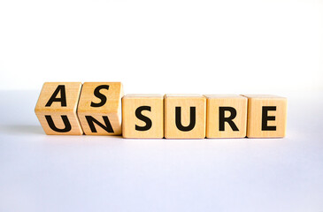 Assure or unsure symbol. Turned wooden cubes and changed the concept word unsure to assure. Beautiful white table, white background, copy space. Business and assure or unsure concept.