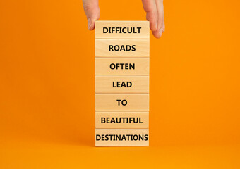 Motivational symbol. Blocks with words Difficult roads often lead to beautiful destinations. Beautiful orange background, copy space. Businessman hand. Business, psychology and motivational concept.