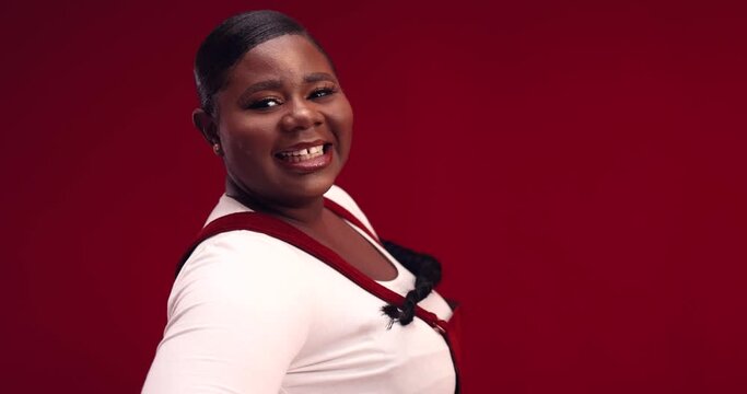 happy young african american woman with long hair braid whirling around on red background