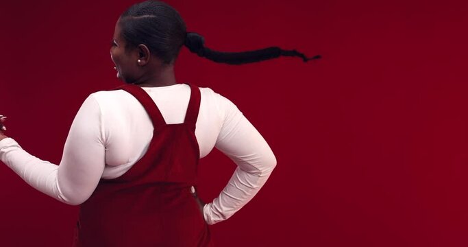 happy young african american woman with long hair braid whirling around on red background