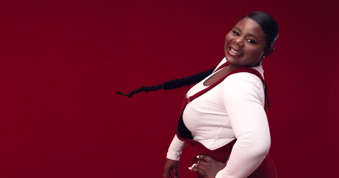 happy young african american woman with long hair braid whirling around on red background