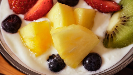 カットフルーツのヨーグルトと木製のスプーン