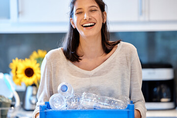 Mom leading by example. Shot of a young woman getting ready to recycle some bottles at home.