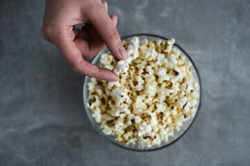 hand takes popcorn from a bowl on the table top view