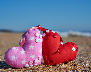 Image of a soft toy in the shape of a heart on the beach.