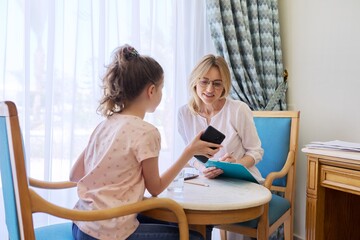Woman teacher, therapist, social worker talking to preteen girl in office.