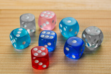 Multicolored playing dice on wooden background.