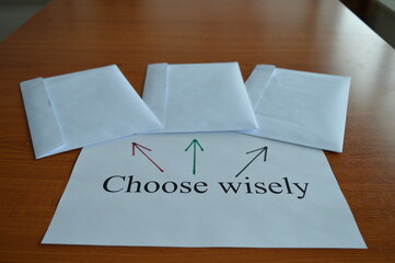 concept photo, three white envelopes on the office desk with the message choose wisely, making...