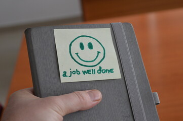 workbook in the hand of an employee with a job well done message and a smiling face, support and a...