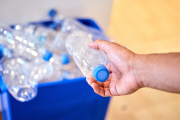 Recycling is a lifestyle. Cropped shot of a man putting a bottle in the recycling bin at home.