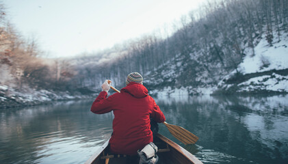 Rear view of man paddling on winter canoe ride