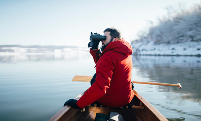 Man watching birds with binoculars  from a canoe