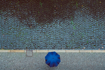 Vogelperspektive auf Straße mit Person mit Regenschirm bei Regen