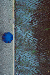 Vogelperspektive auf Straße mit Person mit Regenschirm bei Regen