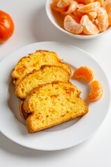 Homemade mandarin cake and tangerine on a plate.