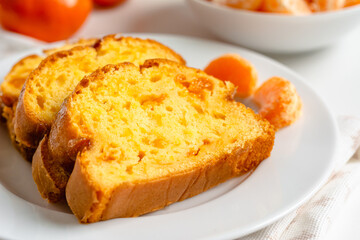 Homemade mandarin cake and tangerine on a plate.