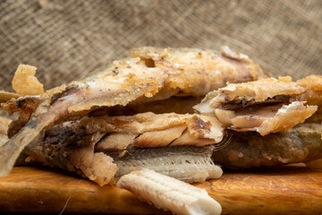 Fried fish and French fries on a cutting board on a wooden table.