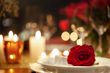 festlich gedeckter Tisch mit roter Rose und Kerzen in warmem Licht
