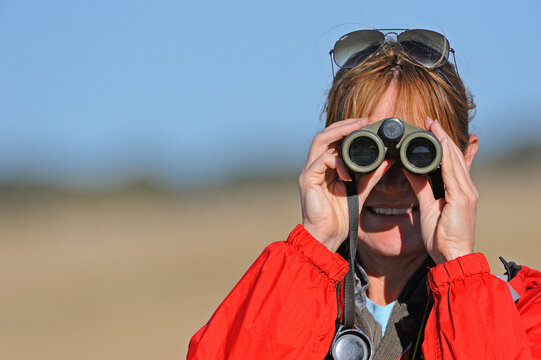 Woman vieing through binoculars, Hwange, Zimbabwe, Africa, MR