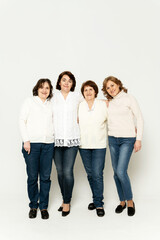 Obraz premium grandmother with daughters stands in full growth on a white background. lovely family. group of women of different ages.