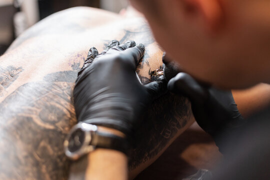 Tattoo master guy in black gloves makes a tattoo, close-up