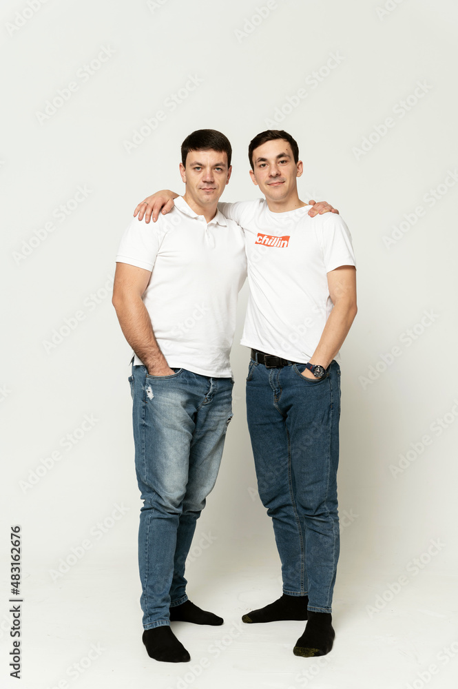 Wall mural two brothers on a white background. older brother with younger. portrait of two friends.