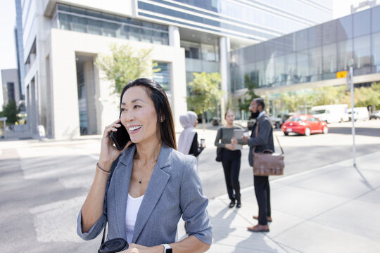 Portrait of asian business executive using phone on city street