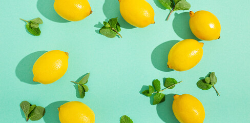 Fresh yellow lemons with mint on minimal blue background on bright sun light with hard shadows pattern summer background flat lay from above, citrus food composition, space for text