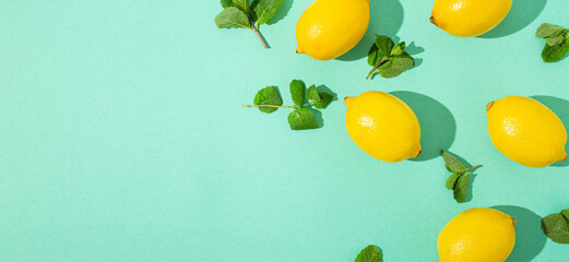 Fresh yellow lemons with mint on minimal blue background on bright sun light with hard shadows pattern summer background flat lay from above, citrus food composition, space for text - obrazy, fototapety, plakaty