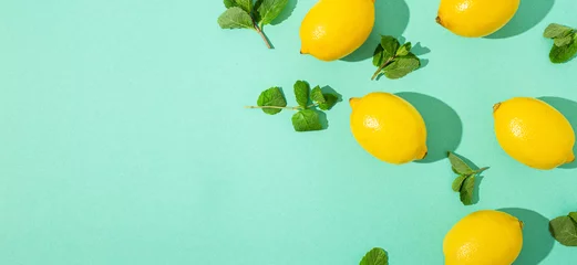 Foto op Plexiglas Fresh yellow lemons with mint on minimal blue background on bright sun light with hard shadows pattern summer background flat lay from above, citrus food composition, space for text © somegirl