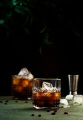Black russian cocktail, trendy alcoholic drink with vodka, coffee liqueur and ice, rusty green background, bar tools, copy space