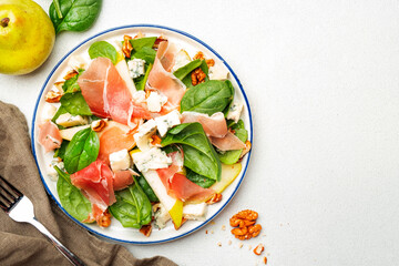 Fototapeta na wymiar Summer pear salad with jamon, blue cheese, spinach and nuts on white table background, top view, copy space