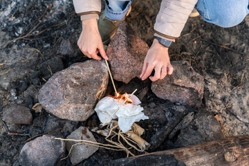 Cropped view of the caucasian woman making campfire while sitting near the rocks at the nature and...