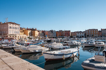 Fototapeta na wymiar Fishing boats anchored in the Rovinj city port, Croatia, during crystal clear winter morning, lit by gentle sun
