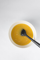 Melted butter, white sugar and an egg mixed in a white bowl