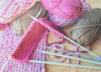 Skeins of thread and knitting needles on wooden background, selective focus.