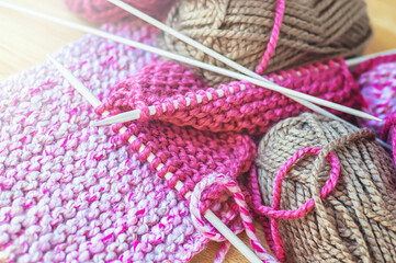 Skeins of thread and knitting needles on wooden background, selective focus.