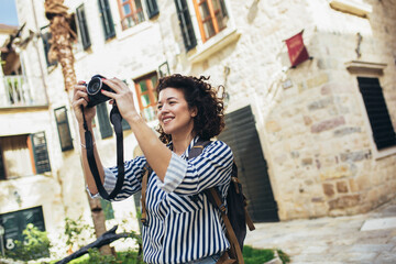 building  outdoors  searching  happiness  camera  photo  trip  curly hair  tourist  happy  europe  urban  travel  street  walking  young  tourism  summer  city  baggage  woman  background  outside  st © Mediteraneo