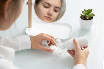 A young woman pours sa solution into a contact lens container