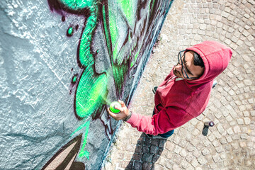 Top view of street artist painting graffiti on generic wall - Modern art concept with urban guy...