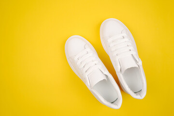 Casual comfortable white shoes.Stylish women's leather shoes with laces on a yellow background. Seasonal sales, promotions, discounts on shoes. Proper care for white skin.Top view.Copyspace