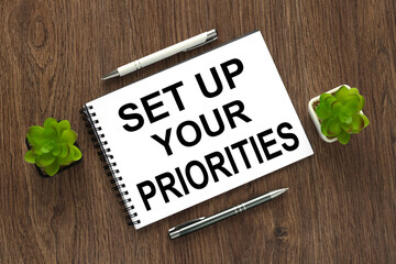 Set up your priorities text written on a notebook with pencils