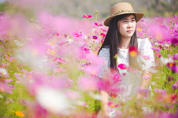 Fototapeta na wymiar Asian woman with white dress relaxing on Margaret Aster flower field in garden 