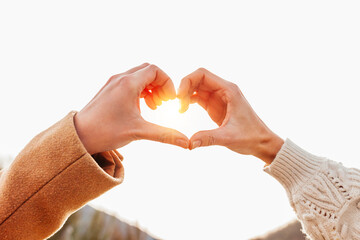 Close up of caucasian female hands in heart shape standing near mountain during winter holidays...