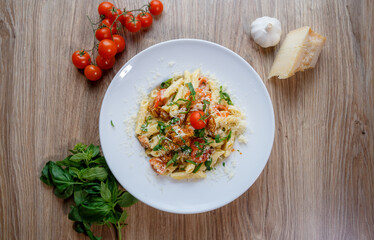 Penne pasta with breadcrumbed chicken breast, cheese, spring onion and tomato top view