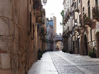 Fototapeta premium calle mayor dela villa medieval de montblanch con bonitos portales dovelados, al fondo uno de los arcos de entrada a la zona amurallada con su torre, tarragona, españa, europa