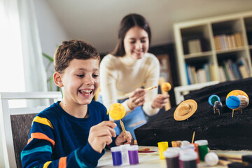 Happy school boy and girl  making a solar system for a school science project at home