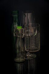 Black background and glass bottles with reflection on table