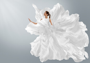 Fashion Model in Creative Pure White Dress as Cloud. Woman in Long Silk Gown with Chiffon Fabric flying on Wind over Light Gray Background. Art Fantasy dancing Girl