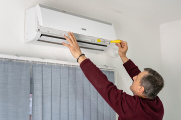 Back view of one senior caucasian man cleaning repairing air-condition at home